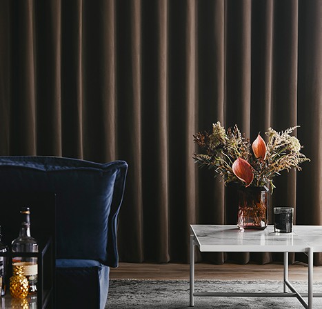 Bruine velours gordijnen Luxaflex fluwelen overgordijnen blauwe bank marmeren tafel hotel chique interieur