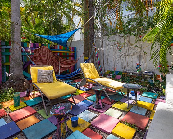 Kleurrijke tuin gekleurde tegels regenboog gele kussens tuinstoelen