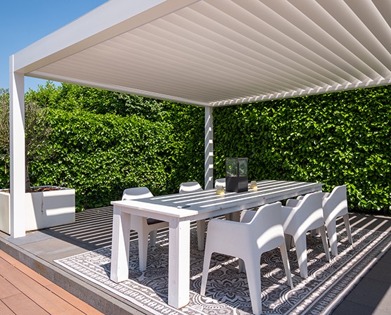 Witte overkapping Ibiza style lamellendak shutters veranda eettafel witte stoelen beach club