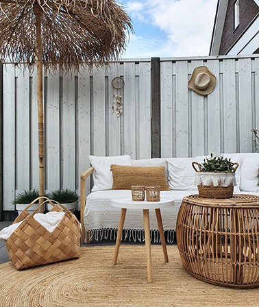 Ibiza tuin inpsiratie boho tuindecoratie jute rond vloerkleed rotan tuinmeubilair boho dromenvanger hoed wanddecoratie